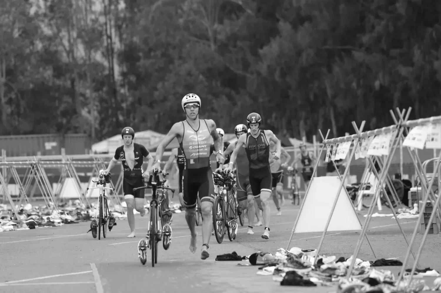 Triathletes running their bikes out of transition