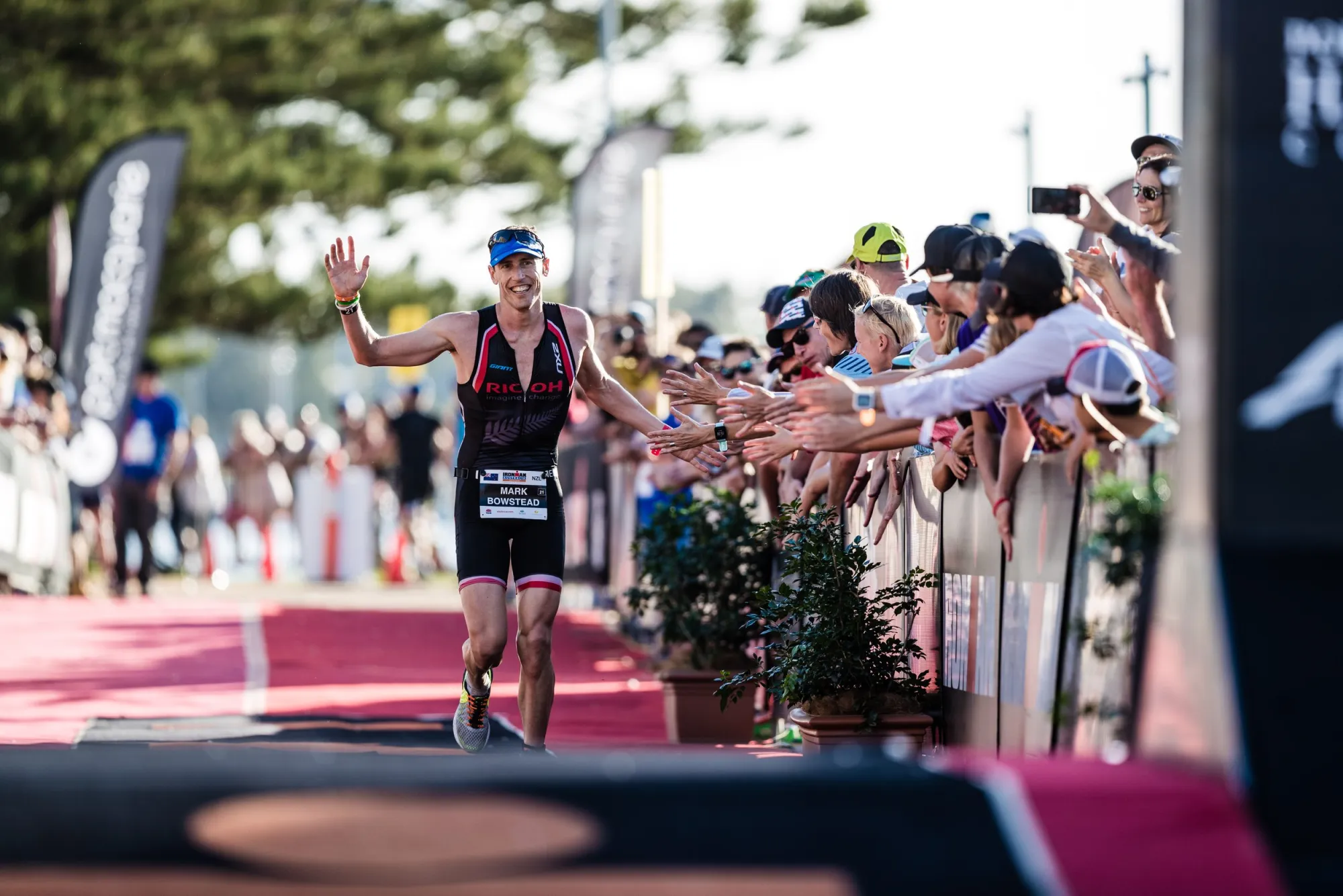 A triathlete high-fiving spectators at a race finish